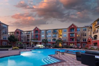 a swimming pool at dusk with an apartment building in the background